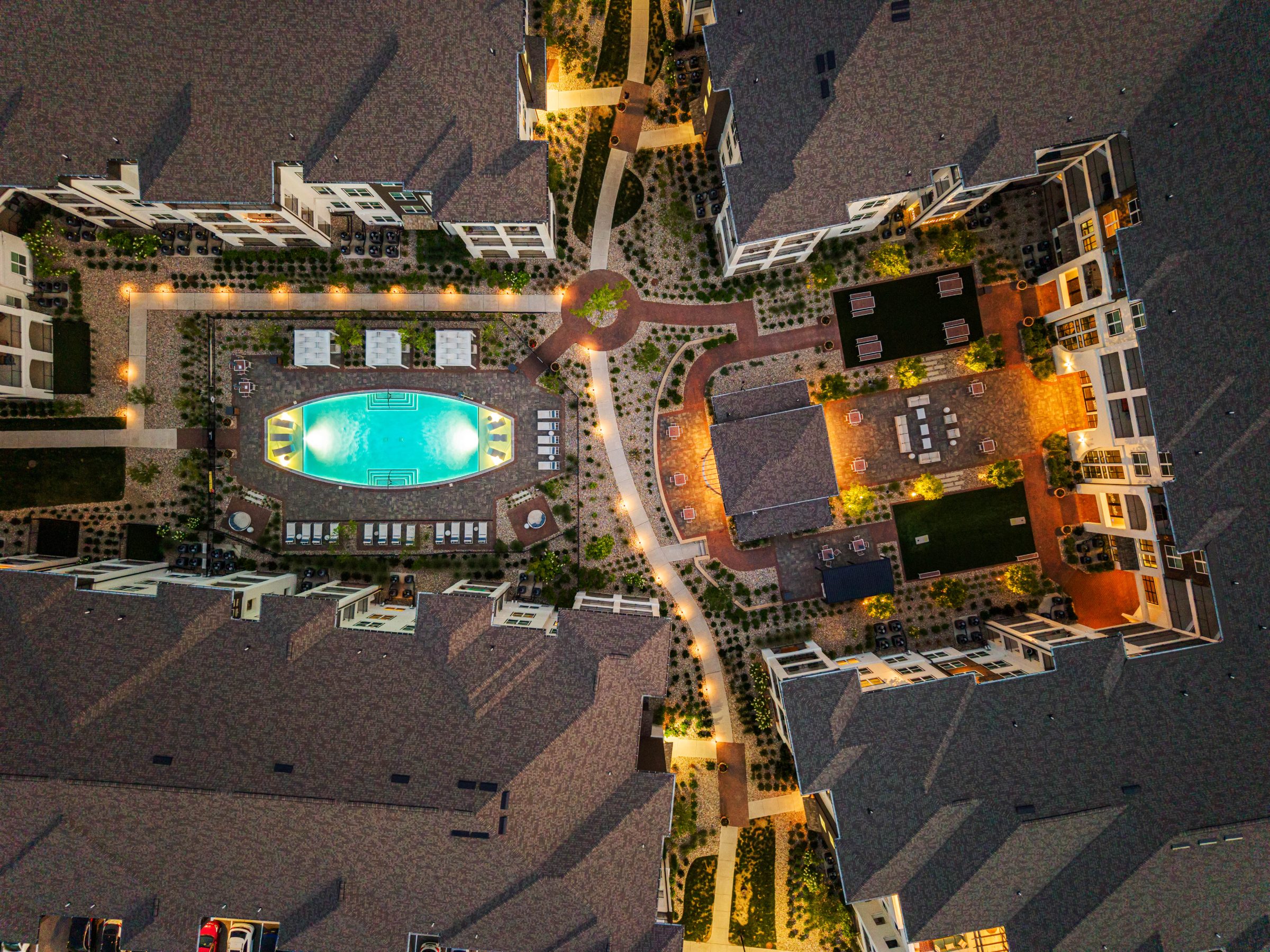 Twilight top-down aerial of the lit pool courtyard at Velo Riverside